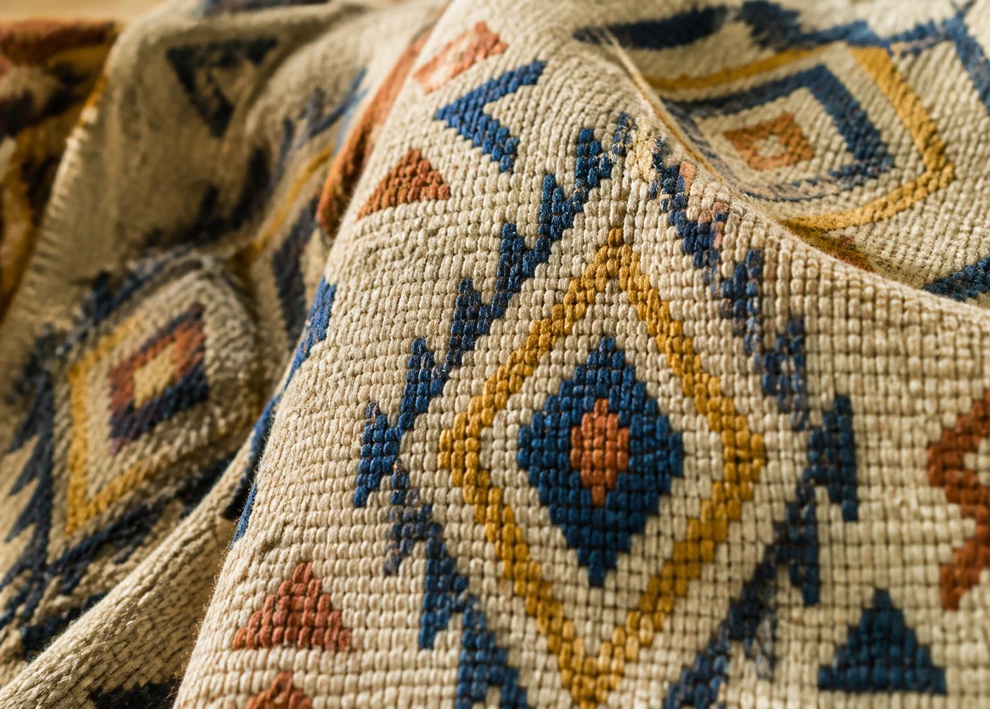 Close-up van geweven Amazigh-textiel met ruitmotieven in blauw, geel en terracotta