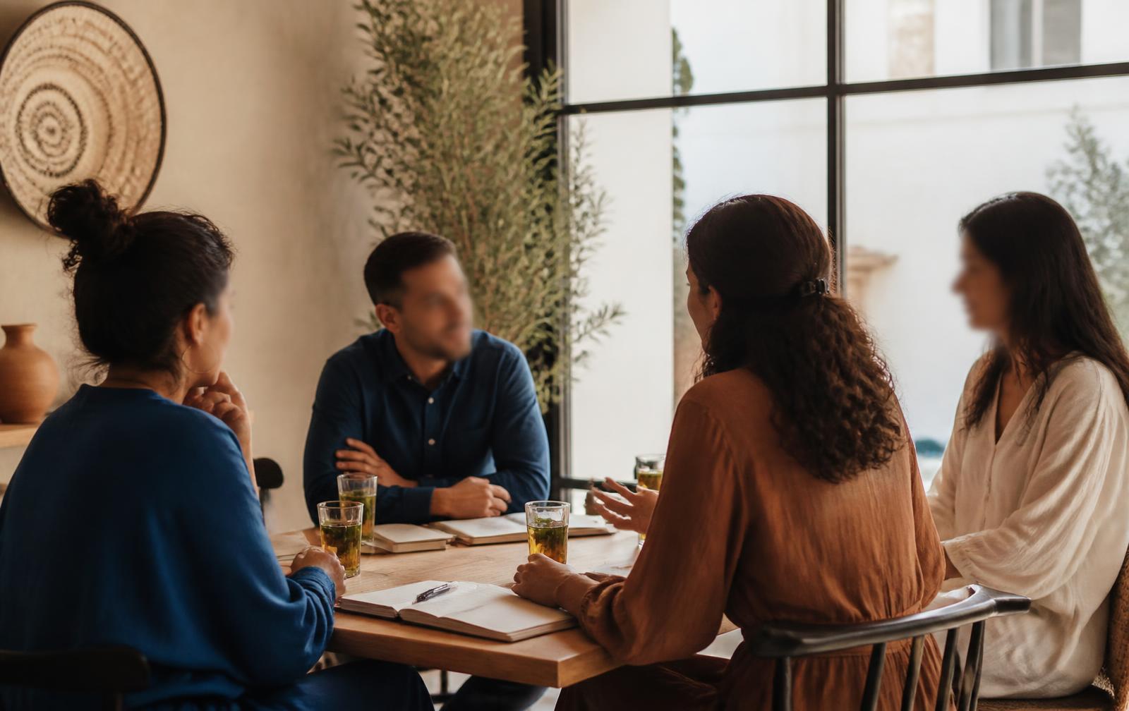 Mensen in gesprek aan een tafel bij warm raamlicht